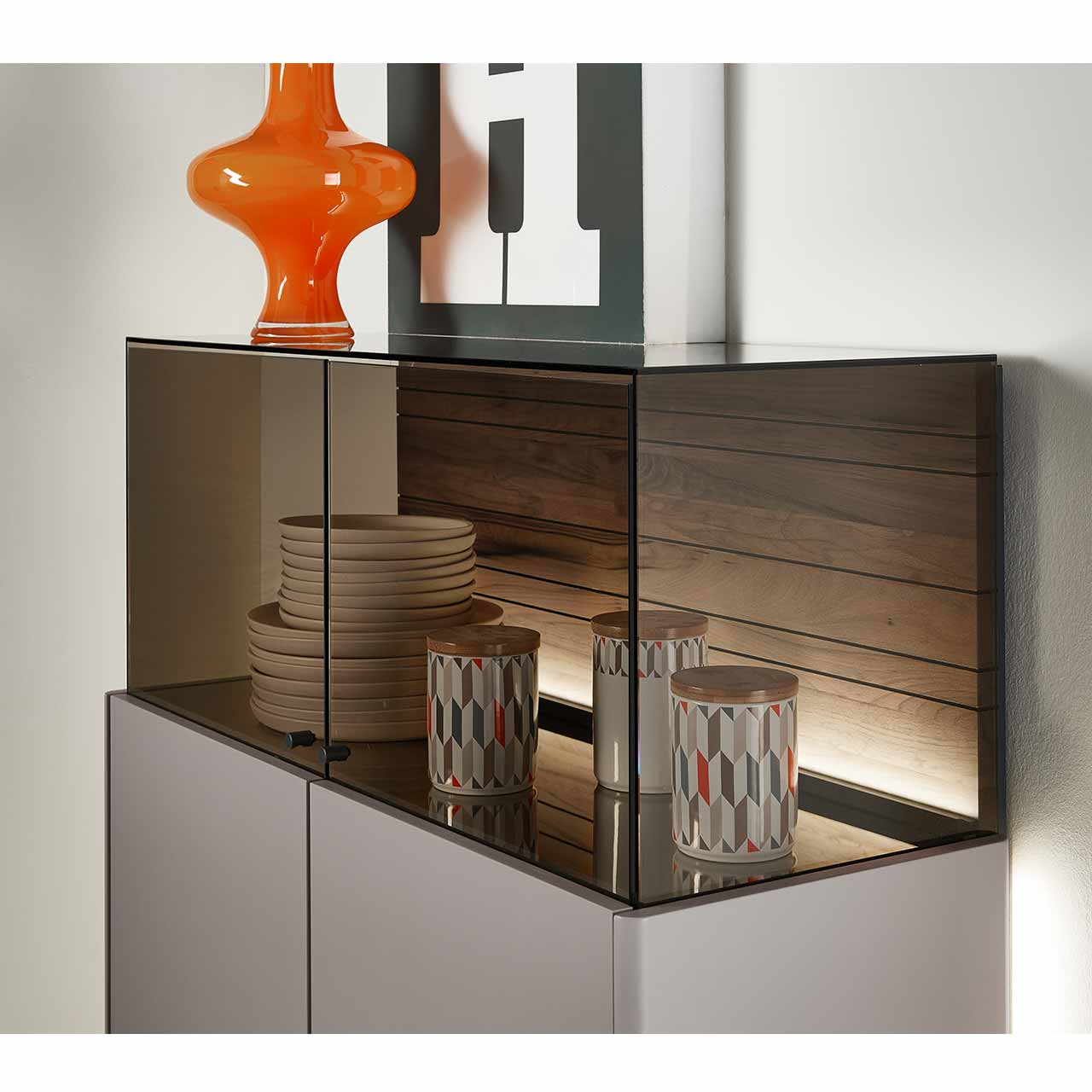 Detailansicht des aufgesetzten Glaskastens des AUDRA Highboards Nr. 7101. Die beleuchtete Rückwand aus Altholz-Buche Uyaa zeigt eine markante, dunkelbraune Holzmaserung.
