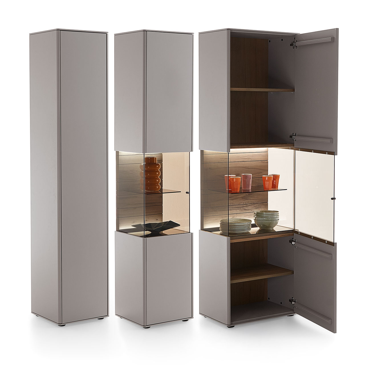 Zwei Standvitrinen aus Massivholz mit sandfarbenen Lackfronten und beleuchtetem Glasausschnitt, in zwei Breiten. Die breitere Vitrine mit geöffneter Glas-Holz
