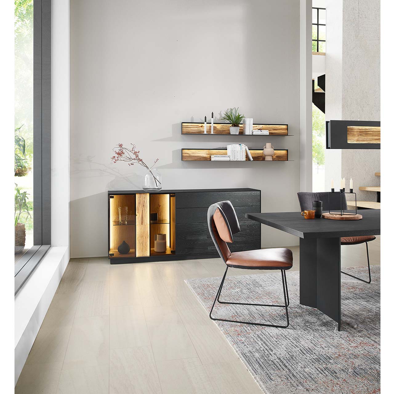 Modernes Sideboard aus massiver Kernesche anthrazit mit Spaltholz-Akzent und Parsolglas-Ausschnitt in einem hellen Raum