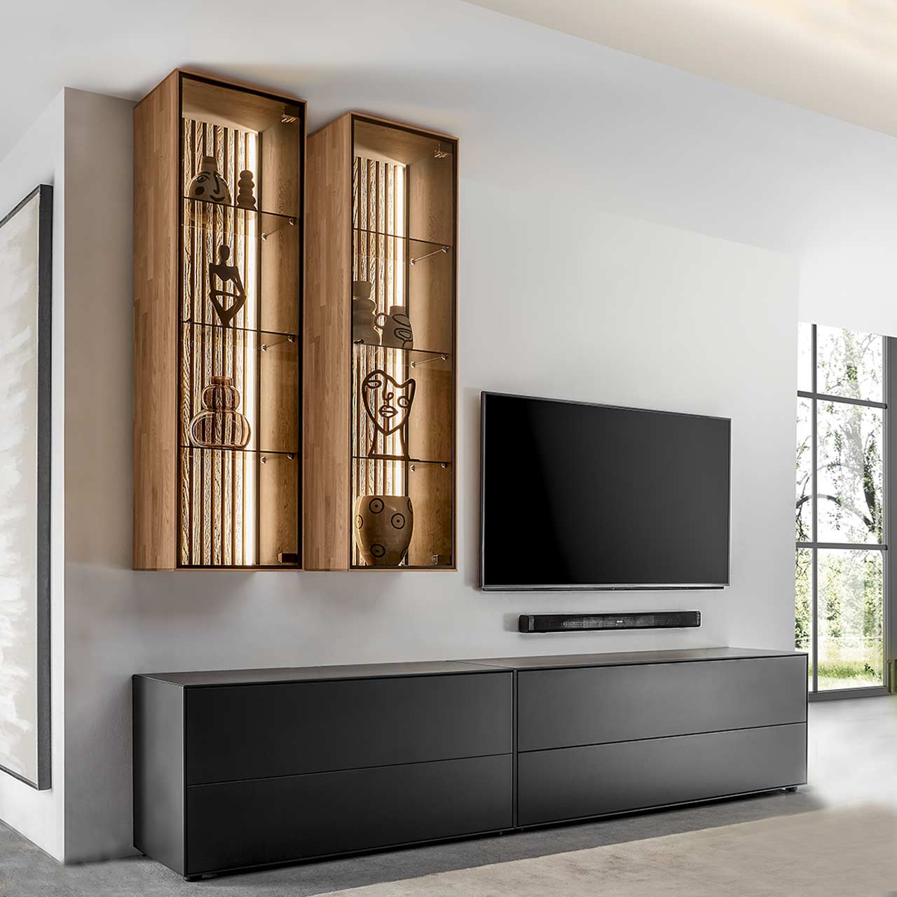 Wohnzimmer mit Fernseher und moderner Massivholz-Wohnwand mit zwei Lowboards aus Birke anthrazit und zwei Hängevitrinen aus heller Kerneiche und Lamellen.