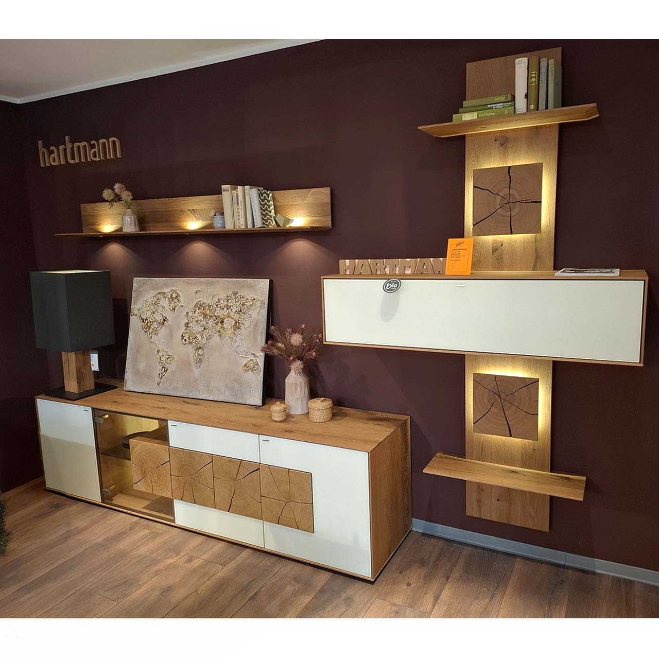 Moderne vierteilige Massivholz Wohnwand aus Kerneiche Umato mit Mattglas weiß Fronten: Lowboard mit Glasausschnitt und Hirnholz, Wandregal aus Holz, schlichter Hängeschrank eingefasst in ein Holzwandpaneel mit Ablageböden.