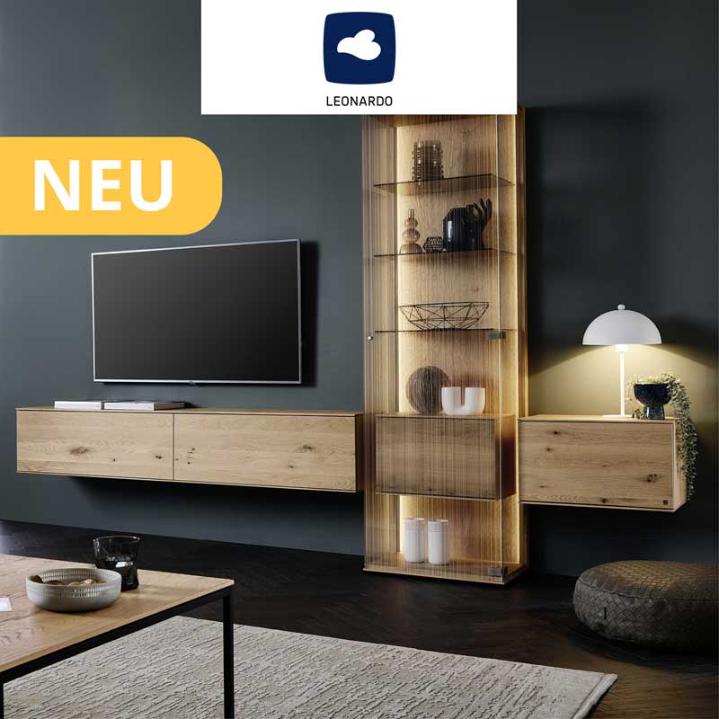Hartmann LINEA - Massivholzmöbel aus Kerneiche Natur kombiniert mit satiniertem Glas. Ambientebild zeigt zwei schlichte Hängelowboards, dazwischen eine Standvitrine aus satiniertem Glas mit integriertem Holzschrank - vor dunkelgrauer Wand